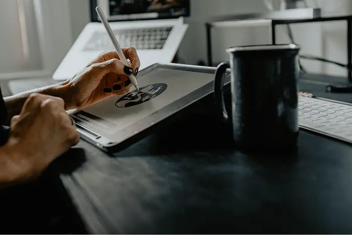 image of designer drawing on ipad with coffee cup off to the side